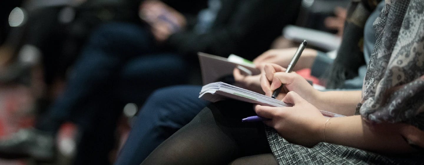 woman writing notes at a business event